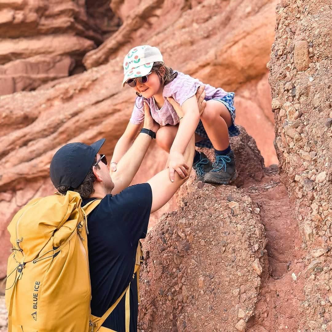 Family hiking a red canyon trail in southern Morocco