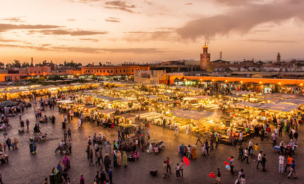 Jemaa el-Fnaa square in Marrakech glowing at dusk with food stalls and the Koutoubia minaret